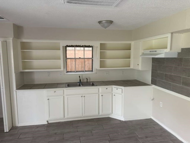 kitchen with dark hardwood / wood-style flooring, white cabinets, sink, and a textured ceiling