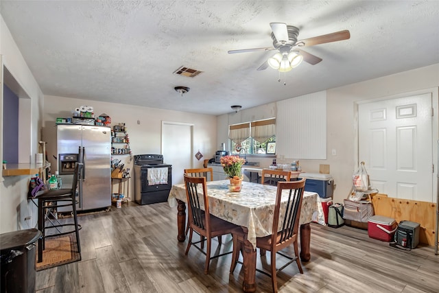 dining area featuring sink, a textured ceiling, light hardwood / wood-style floors, and ceiling fan