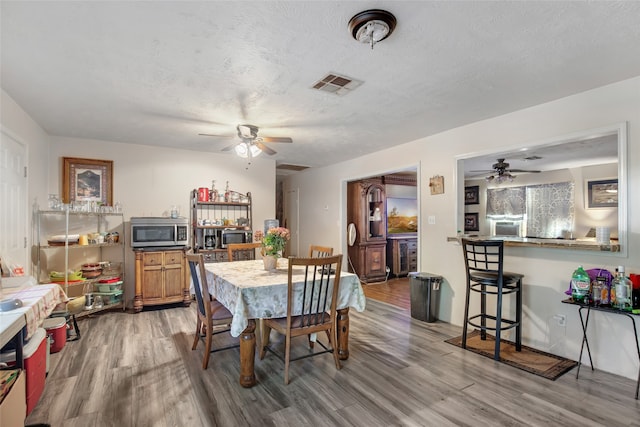 dining space featuring ceiling fan, wood-type flooring, and a textured ceiling