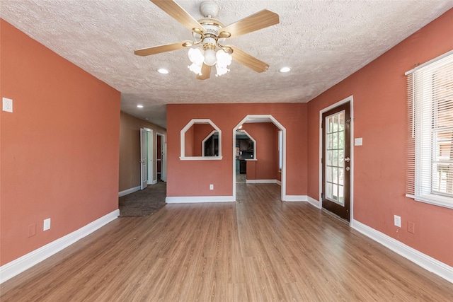 unfurnished living room with a ceiling fan, recessed lighting, a textured ceiling, baseboards, and wood finished floors