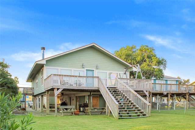 rear view of house featuring a wooden deck, a patio, and a lawn