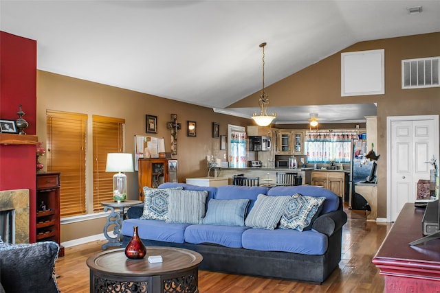 living room featuring lofted ceiling, a tiled fireplace, wood-type flooring, and ceiling fan