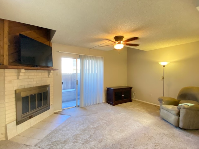 unfurnished room with ceiling fan, a textured ceiling, a brick fireplace, and light colored carpet