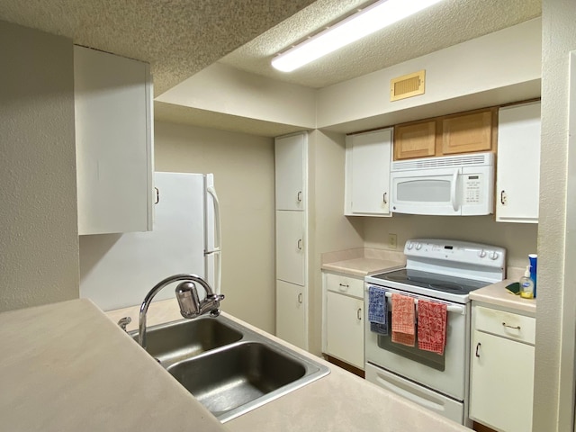 kitchen with a textured ceiling, white cabinets, sink, and white appliances