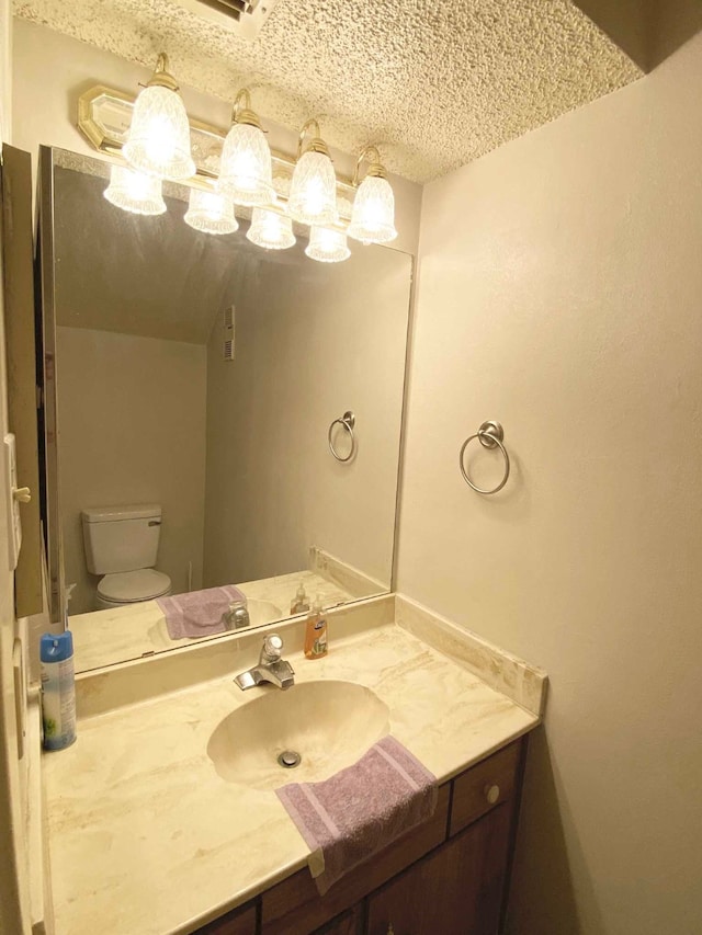 bathroom with vanity, toilet, and a textured ceiling