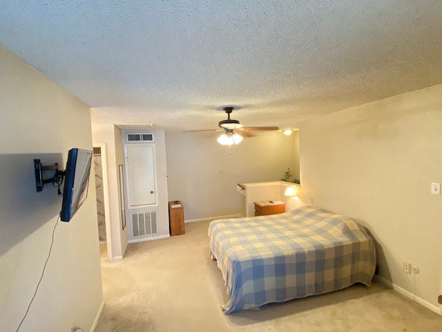 bedroom featuring ceiling fan, light carpet, and a textured ceiling