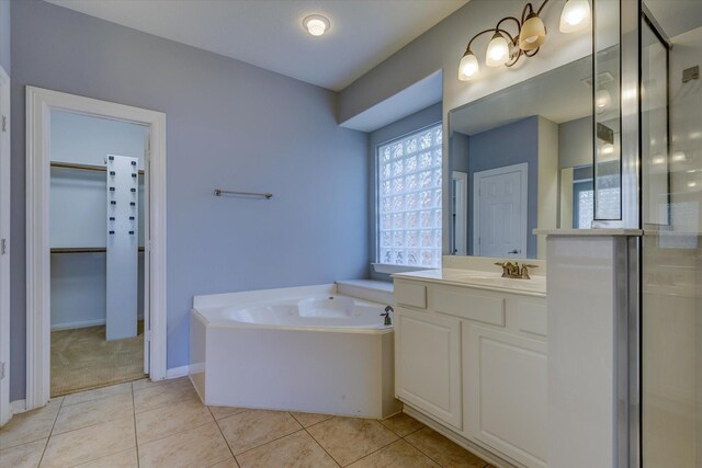 17519 Bighorn River Ln, Humble, TX 77346 - bathroom featuring a garden tub, vanity, a spacious closet, tile patterned flooring, and baseboards