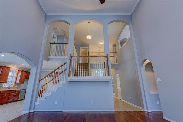 17519 Bighorn River Ln, Humble, TX 77346 - unfurnished living room featuring stairs, light wood-type flooring, a towering ceiling, ornamental molding, and baseboards