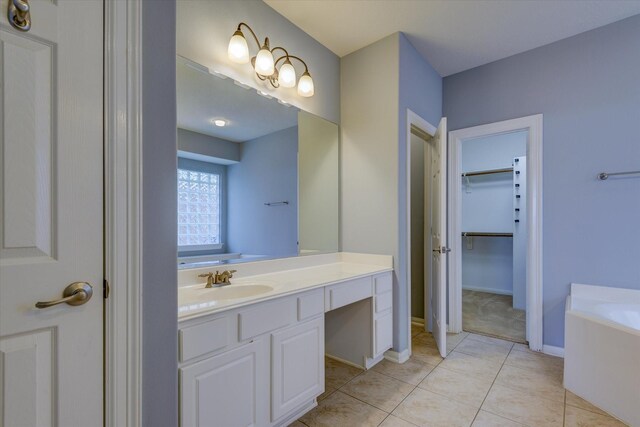 17519 Bighorn River Ln, Humble, TX 77346 - bathroom featuring vanity, a garden tub, a spacious closet, tile patterned flooring, and baseboards