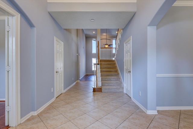 entryway with ceiling fan, crown molding, and light tile patterned floors