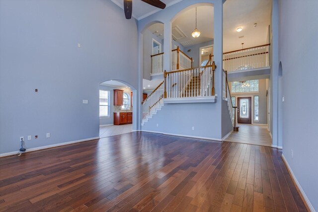 17519 Bighorn River Ln, Humble, TX 77346 - unfurnished living room featuring stairway, a towering ceiling, wood finished floors, arched walkways, and baseboards