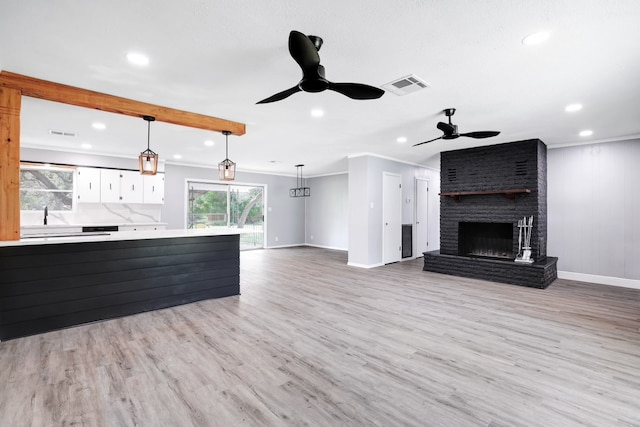 unfurnished living room with a fireplace, light hardwood / wood-style floors, ceiling fan, and crown molding