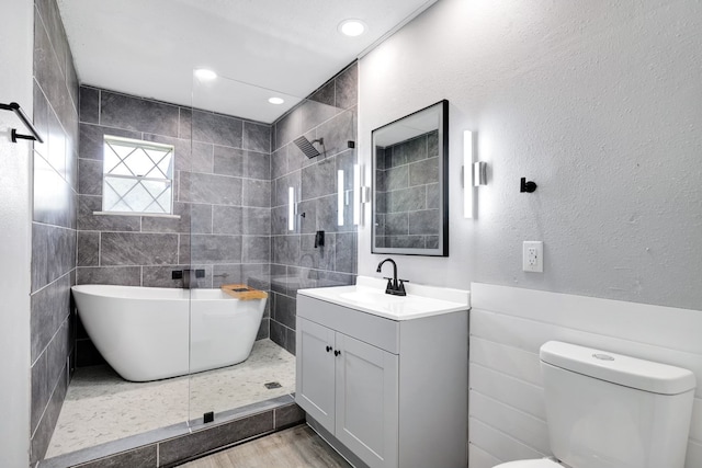 full bathroom featuring tile walls, wood-type flooring, shower with separate bathtub, vanity, and toilet