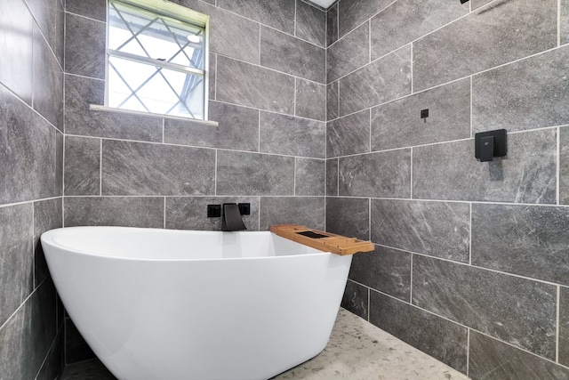 bathroom with a tub and tile walls