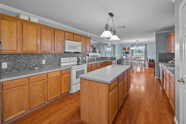 kitchen with hanging light fixtures, light hardwood / wood-style flooring, ornamental molding, a center island, and white appliances