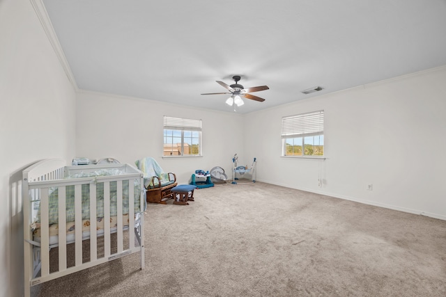 carpeted bedroom featuring ceiling fan, ornamental molding, multiple windows, and a crib