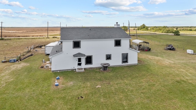 back of property featuring a yard and a rural view