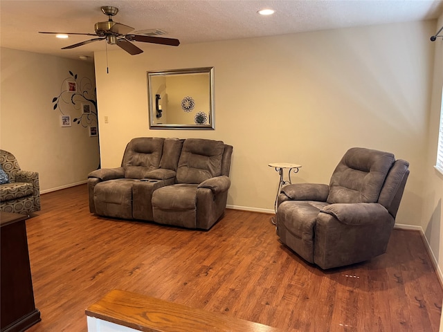 living room featuring a textured ceiling, wood-type flooring, and ceiling fan