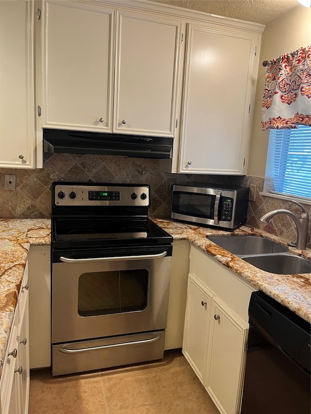 kitchen featuring decorative backsplash, appliances with stainless steel finishes, white cabinetry, light stone countertops, and sink