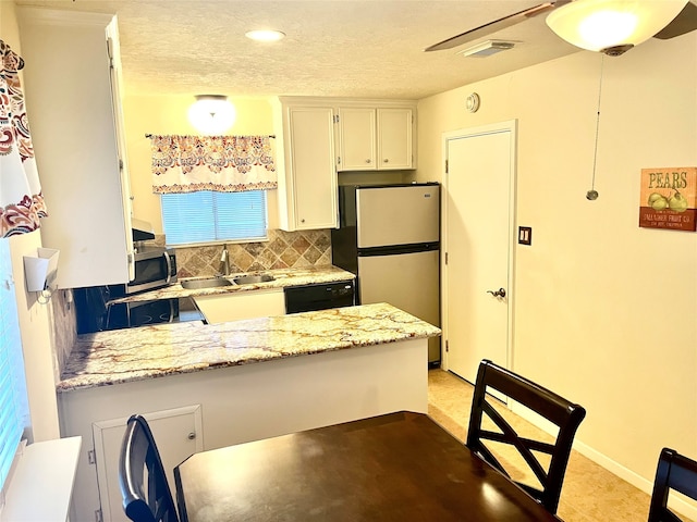 kitchen featuring stainless steel appliances, sink, white cabinets, light stone counters, and tasteful backsplash