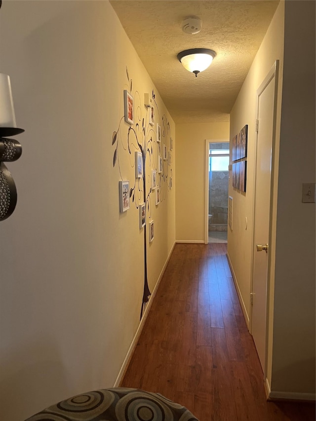 hall with dark wood-type flooring and a textured ceiling