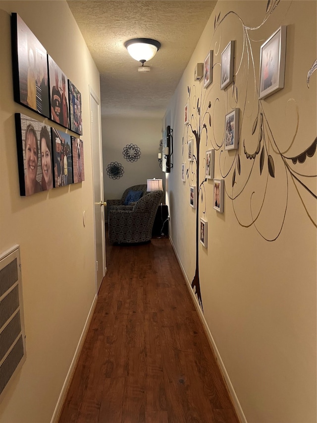 hallway featuring a textured ceiling and dark wood-type flooring