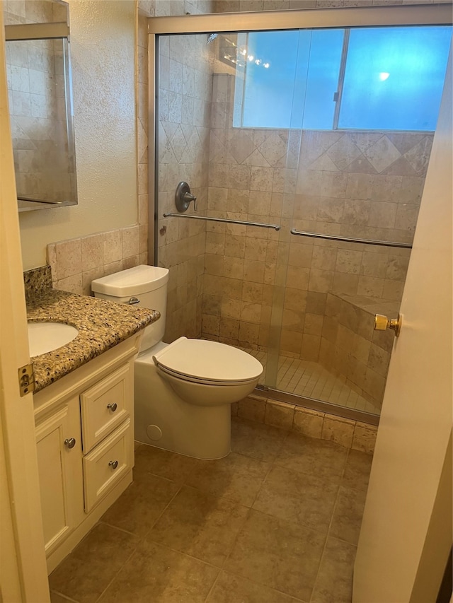 bathroom with vanity, toilet, tile patterned floors, and a shower with door