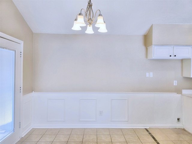 unfurnished dining area with a notable chandelier and light tile patterned floors