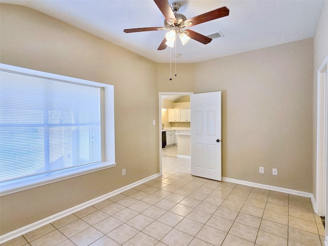 tiled spare room featuring ceiling fan