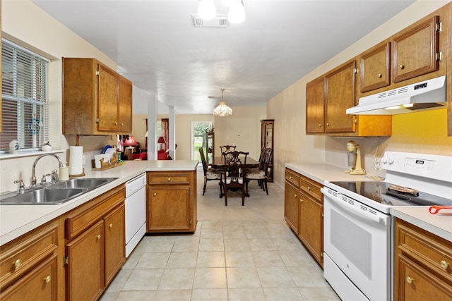 kitchen with white appliances, light tile patterned flooring, sink, kitchen peninsula, and decorative light fixtures