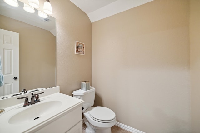 bathroom featuring vanity, toilet, and lofted ceiling