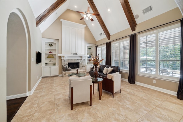 tiled living room featuring ceiling fan, a stone fireplace, built in features, high vaulted ceiling, and beamed ceiling