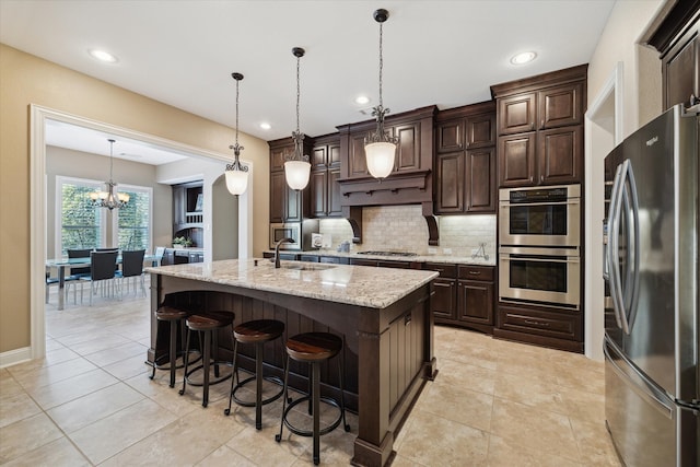 kitchen with pendant lighting, dark brown cabinetry, stainless steel appliances, and a center island with sink