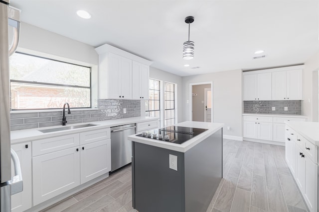 kitchen with stainless steel dishwasher, a kitchen island, white cabinetry, and a wealth of natural light