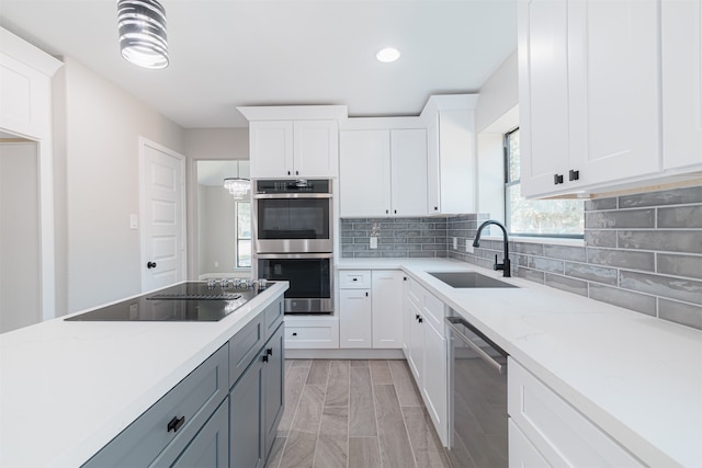 kitchen with light stone countertops, sink, white cabinets, and stainless steel appliances