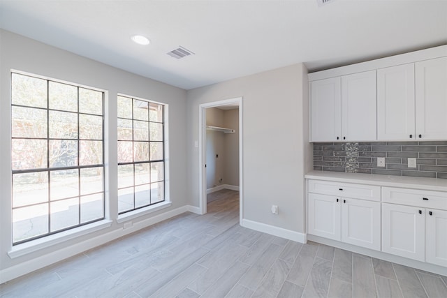 kitchen with light hardwood / wood-style floors, white cabinetry, and tasteful backsplash