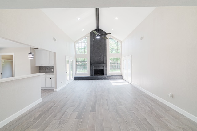 unfurnished living room featuring beam ceiling, ceiling fan, high vaulted ceiling, a brick fireplace, and light hardwood / wood-style flooring