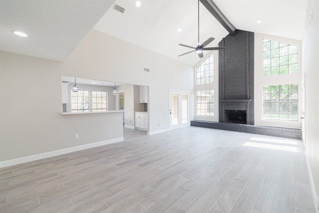 unfurnished living room featuring light hardwood / wood-style floors, high vaulted ceiling, a wealth of natural light, and a brick fireplace