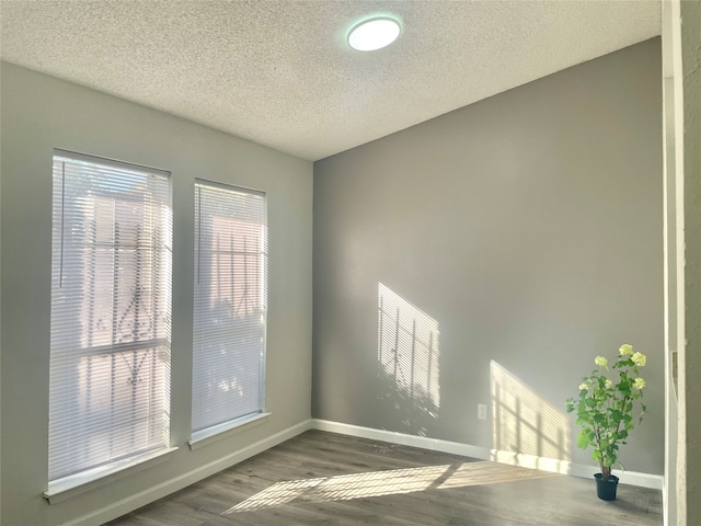 unfurnished room featuring plenty of natural light, dark hardwood / wood-style flooring, and a textured ceiling