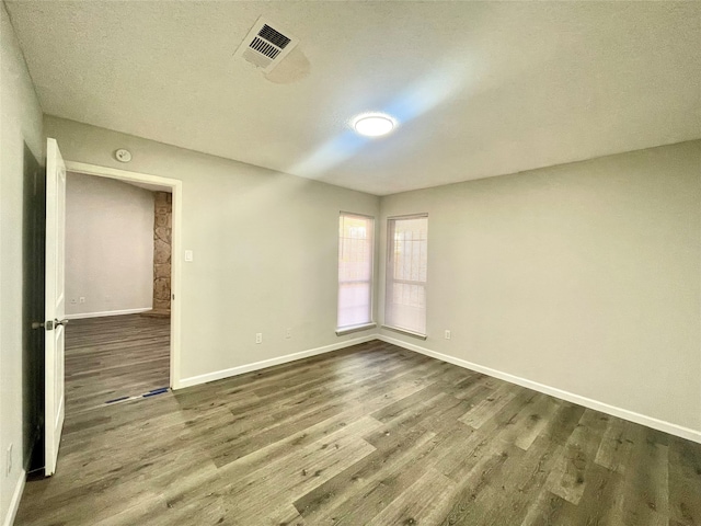 empty room featuring a textured ceiling and dark wood-type flooring