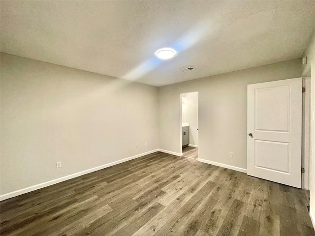 unfurnished room featuring dark hardwood / wood-style flooring and a textured ceiling