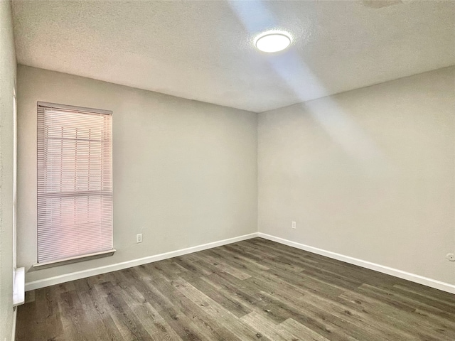 empty room featuring a textured ceiling and dark hardwood / wood-style floors