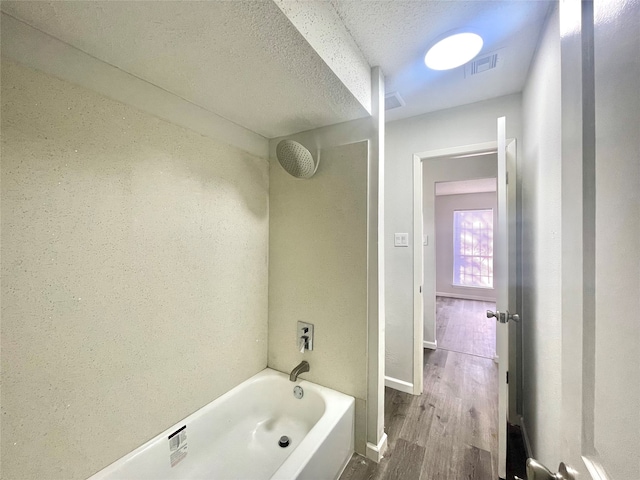 bathroom featuring hardwood / wood-style flooring, a textured ceiling, and bathtub / shower combination