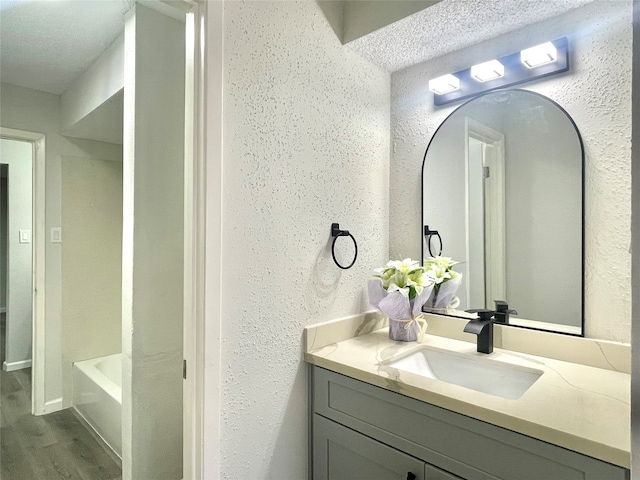 bathroom featuring a bathtub, vanity, wood-type flooring, and a textured ceiling