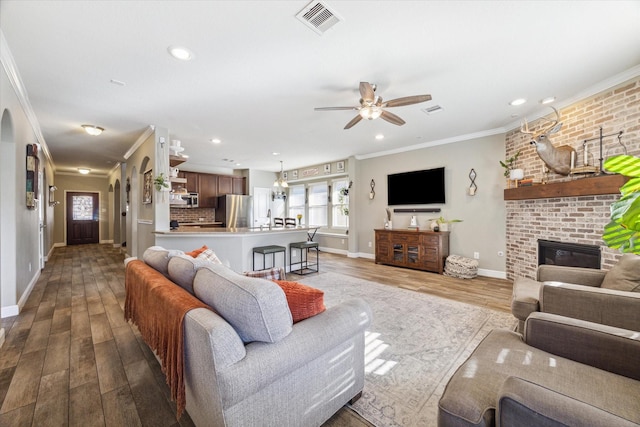 living room with a fireplace, light hardwood / wood-style floors, ceiling fan, and ornamental molding