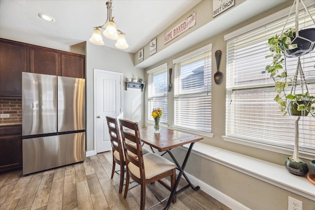 dining space with light hardwood / wood-style floors and an inviting chandelier