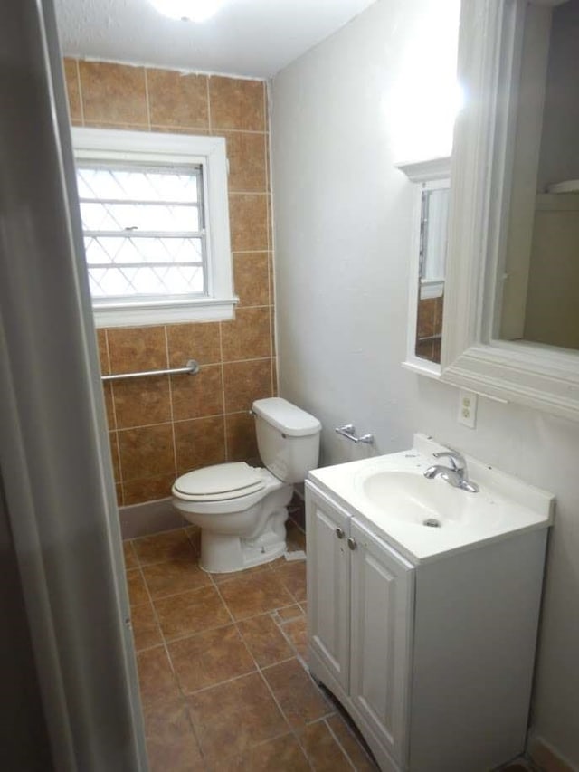 bathroom with vanity, toilet, tile walls, and tile patterned flooring