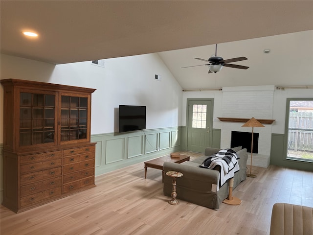 living room with light hardwood / wood-style flooring, a healthy amount of sunlight, a fireplace, and ceiling fan