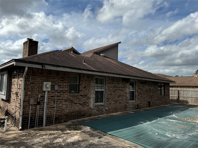 rear view of house featuring a covered pool