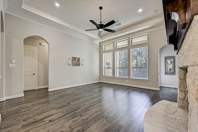 unfurnished living room with ornamental molding, a tray ceiling, ceiling fan, and dark wood-type flooring